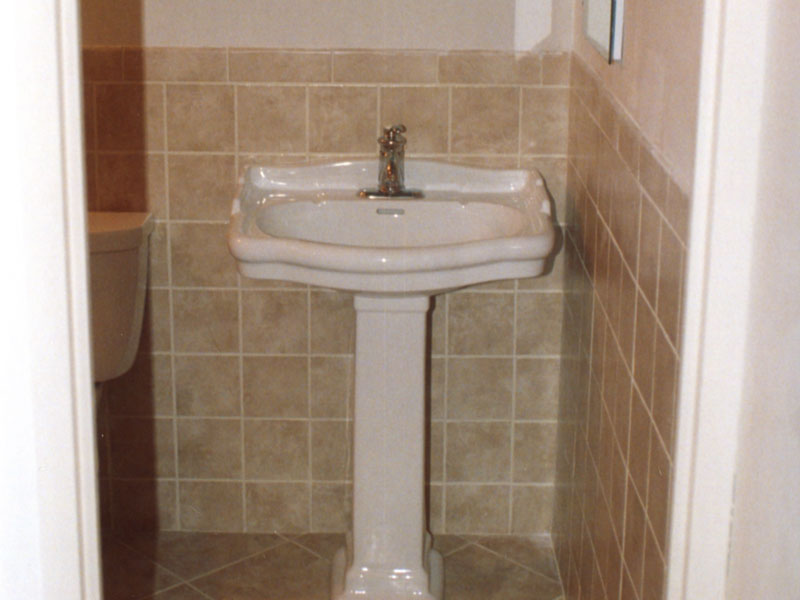 New pedestal sink with ceramic tile halfway up the wall and on the floor
