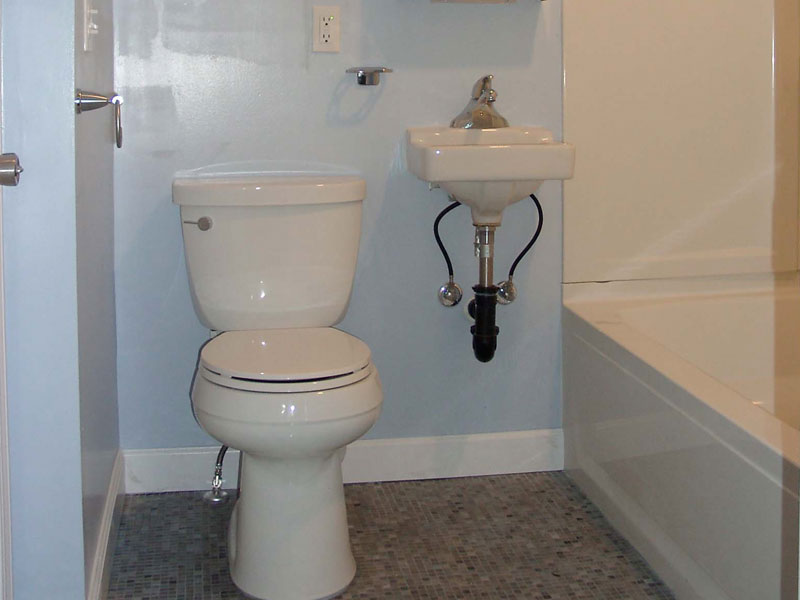 New full bath in home, showing tiled floor and space-saving sink.